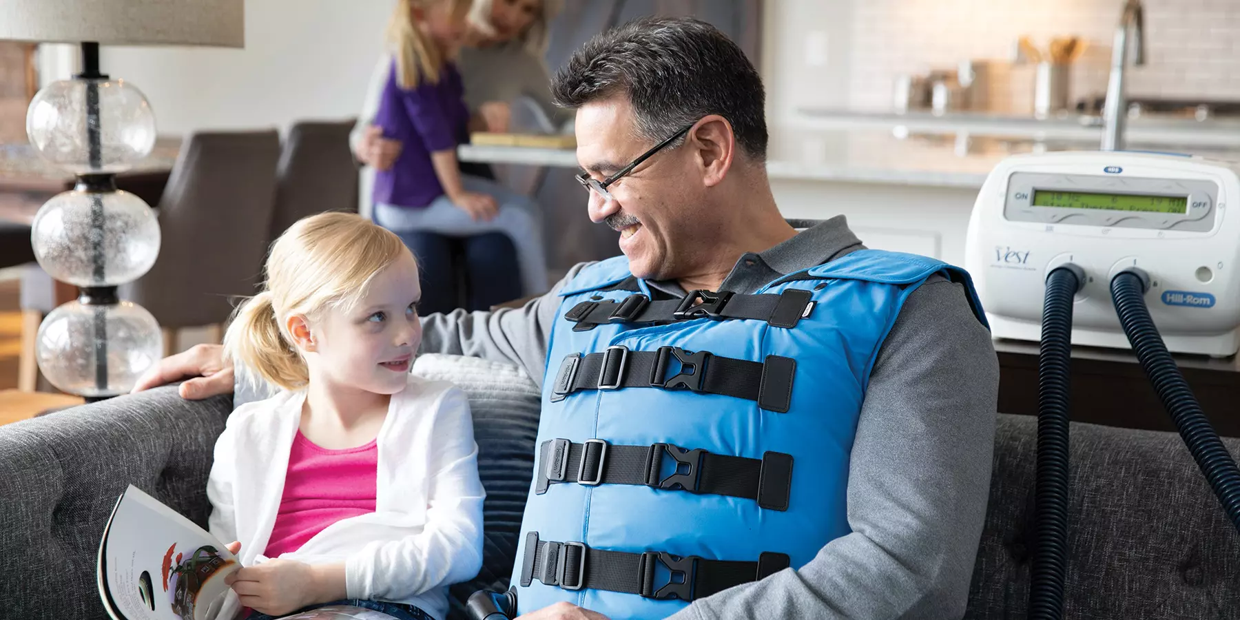 Patient using airway clearance vest at home with family